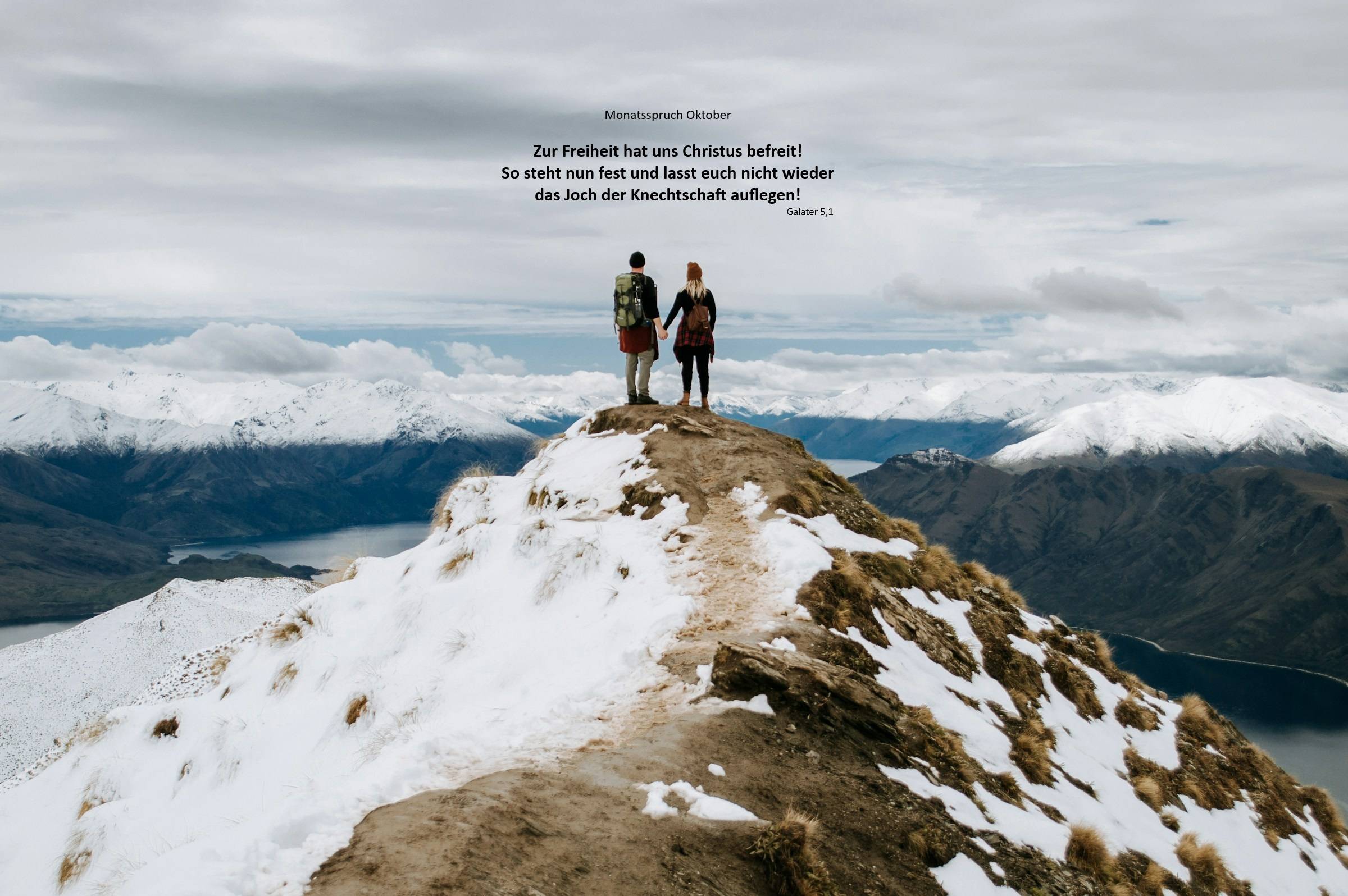 Quelle: Katie McBroom, Katie McBroom + Unsplash, Katie McBroom Zwei Menschen auf Berggipfel, mit weitem Blick ins Land, sicher stehend.